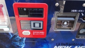 An electronic card reader next to the coin input on a cigarette vending machine.