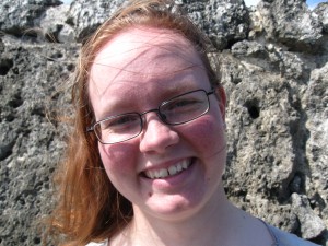 Red haired young woman infront of a rock wall.