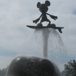 A metal Mickey Mouse surfing a whale's sprout