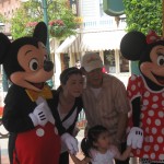 Mickey Mouse and Minnie Mouse characters posing for a picture with an Asian family