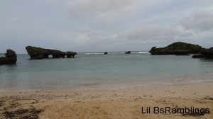 A beach with smallwaves crashing against distant rock formations.