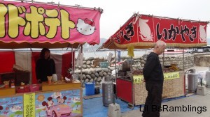 A deer is calmly exploring behind two food booths as no human pays attention.