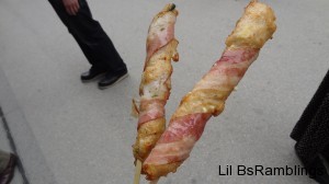 Two dough rolls wrapped in bacon on sticks for easy eating