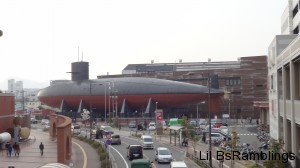 A Japanese submarine towering three or four floors above the cars driving by it.