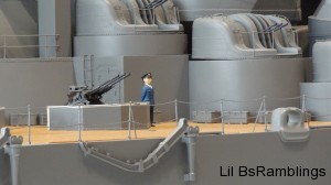This is a plastic model of a Japanese military man standing next to a gun on the main deck of the ship.