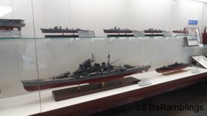 Four model battleships in a display case.