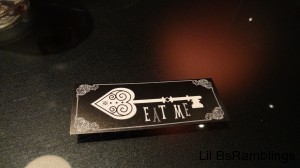 A business card decorated with a fancy skeleton key that says "Eat Me" under the key.