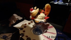 A pastry decorated with fruit in front and a bun for a tail in back of the icecream look like the famous cat.