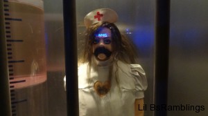 A plastic figure stands behind glass in a nurse outfit but with its heart removed.