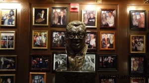 A bust of Harry Carry in front of photos of him with famous people.