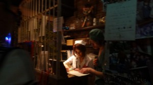 A nurse and male orderly behind some paper-covered bars looking at a book